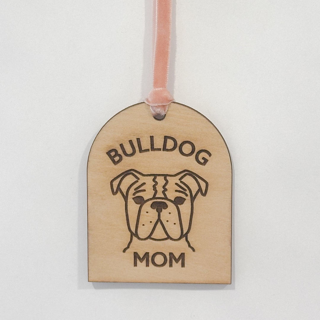 A wooden arch-shaped gift tag with a pink ribbon loop, featuring a laser-engraved bulldog face and the words &
