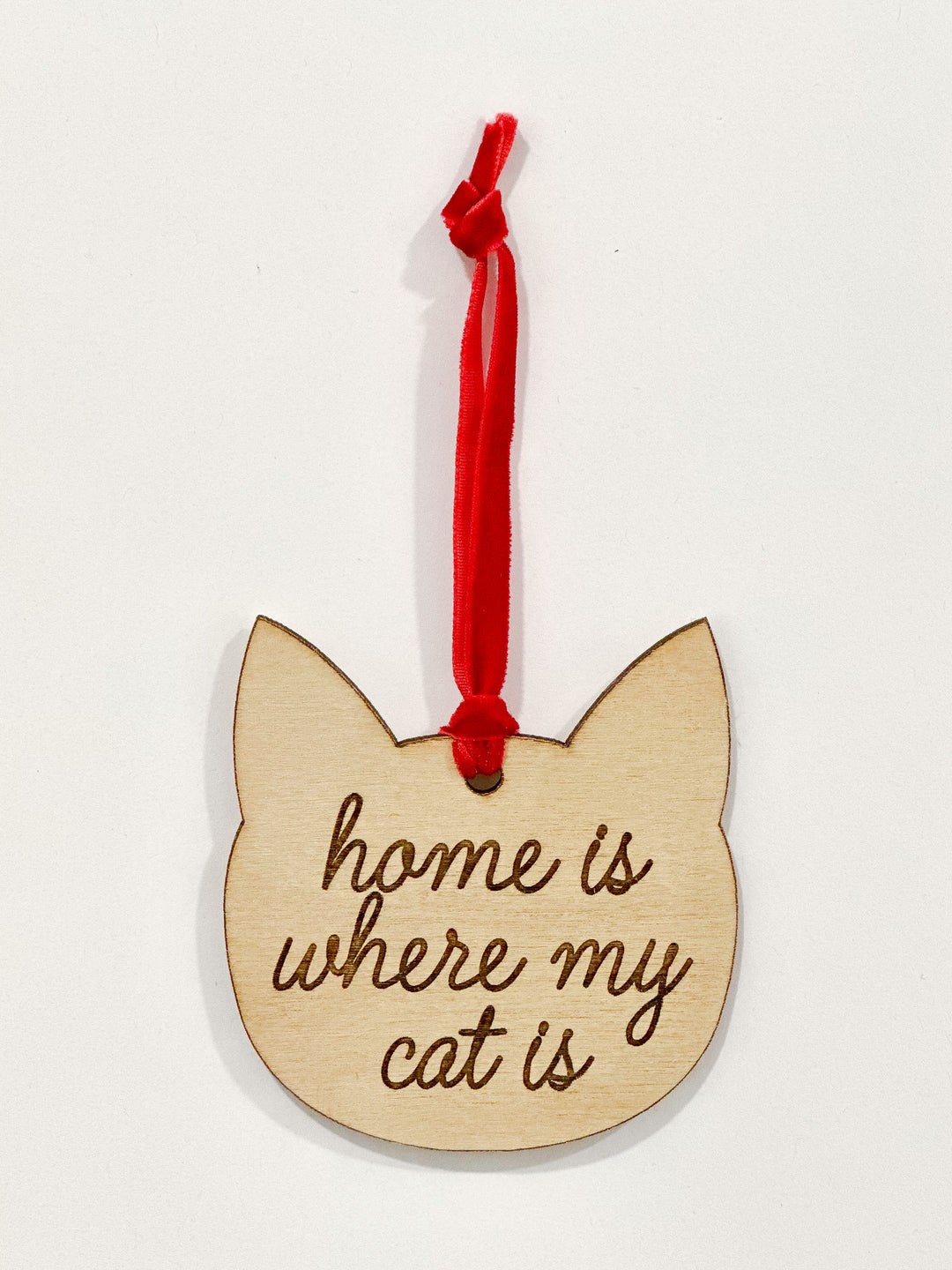 A wooden cat-shaped ornament with the engraved phrase &