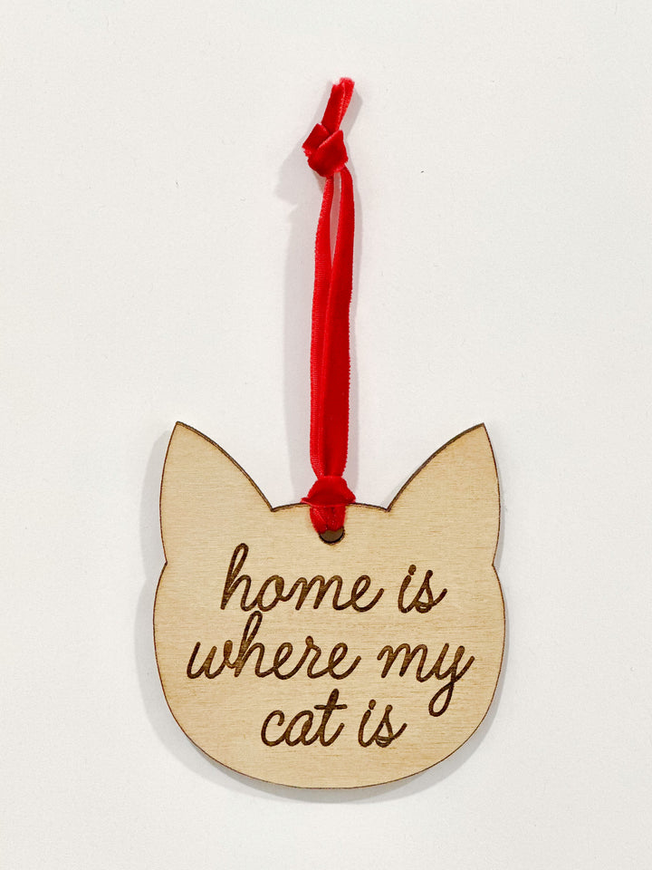 A wooden cat-shaped ornament with the engraved phrase &