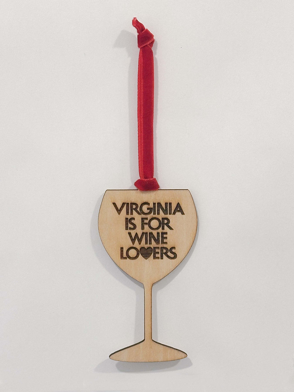 A wooden wine glass shaped ornament with the text 'VIRGINIA IS FOR WINE LOVERS' in black, hanging from a red ribbon on a plain white background.